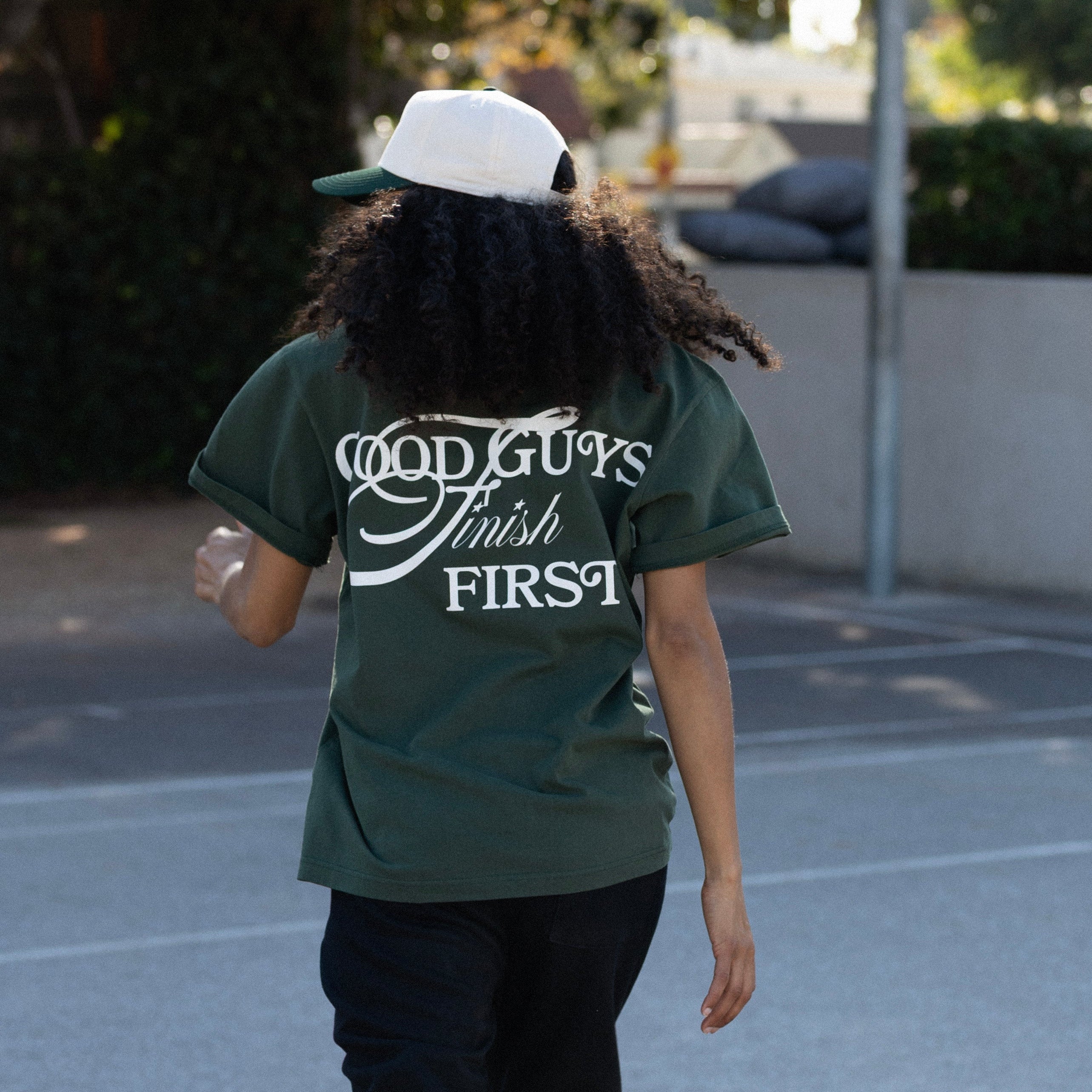 Person wearing a green t-shirt with 'Good Guys Finish First' text outdoors.