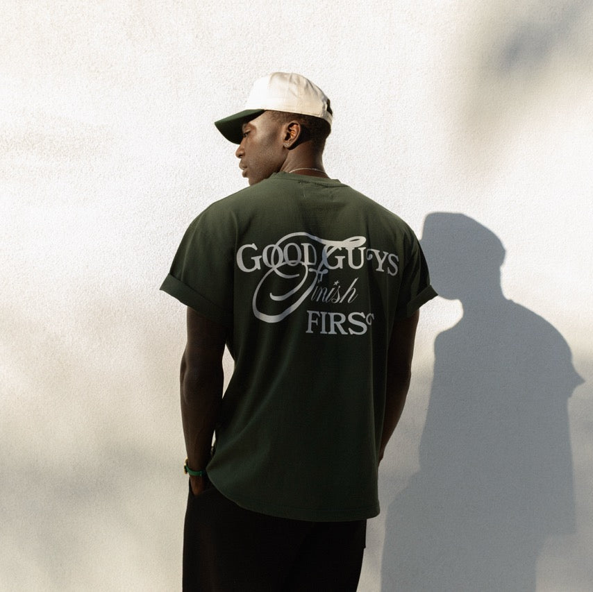 Person wearing a green t-shirt with 'Good Guys Finish First' text, standing against a light background.