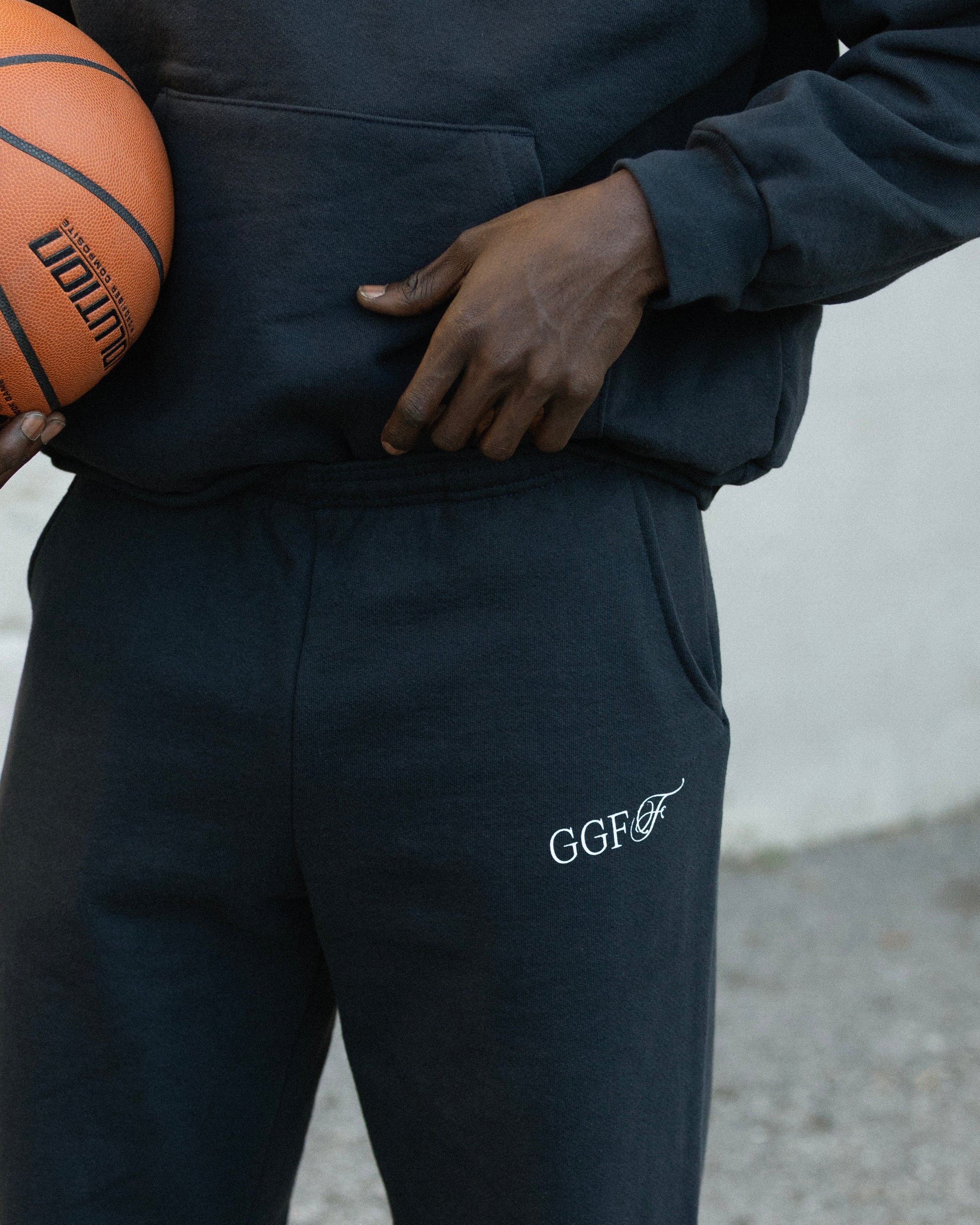 Person wearing a navy tracksuit with 'GGFF' logo holding a basketball.