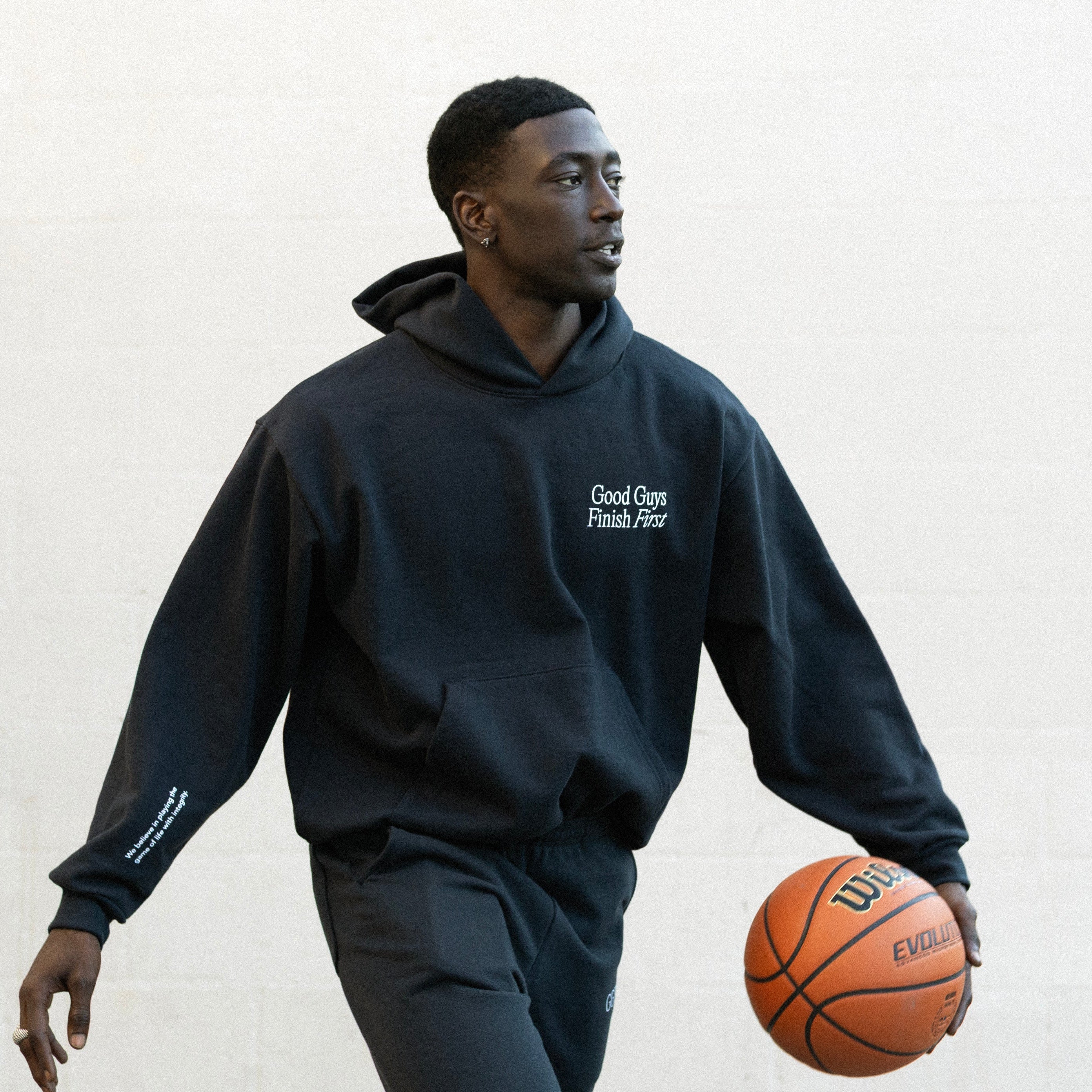 Person wearing a navy hoodie with text, holding a basketball against a white background