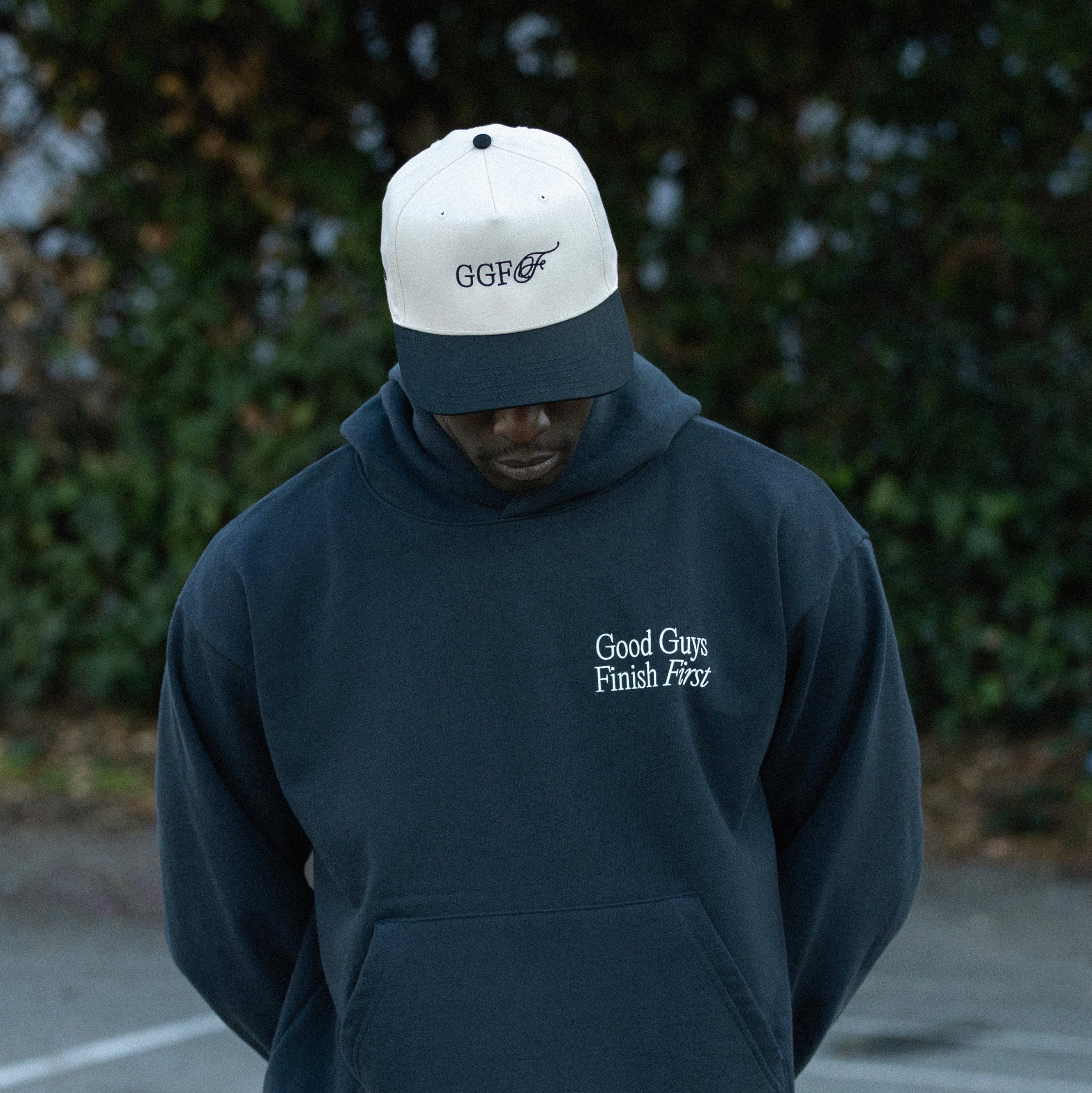 Person wearing a navy hoodie and pants with 'Good Guys Finish First' text, standing outdoors.