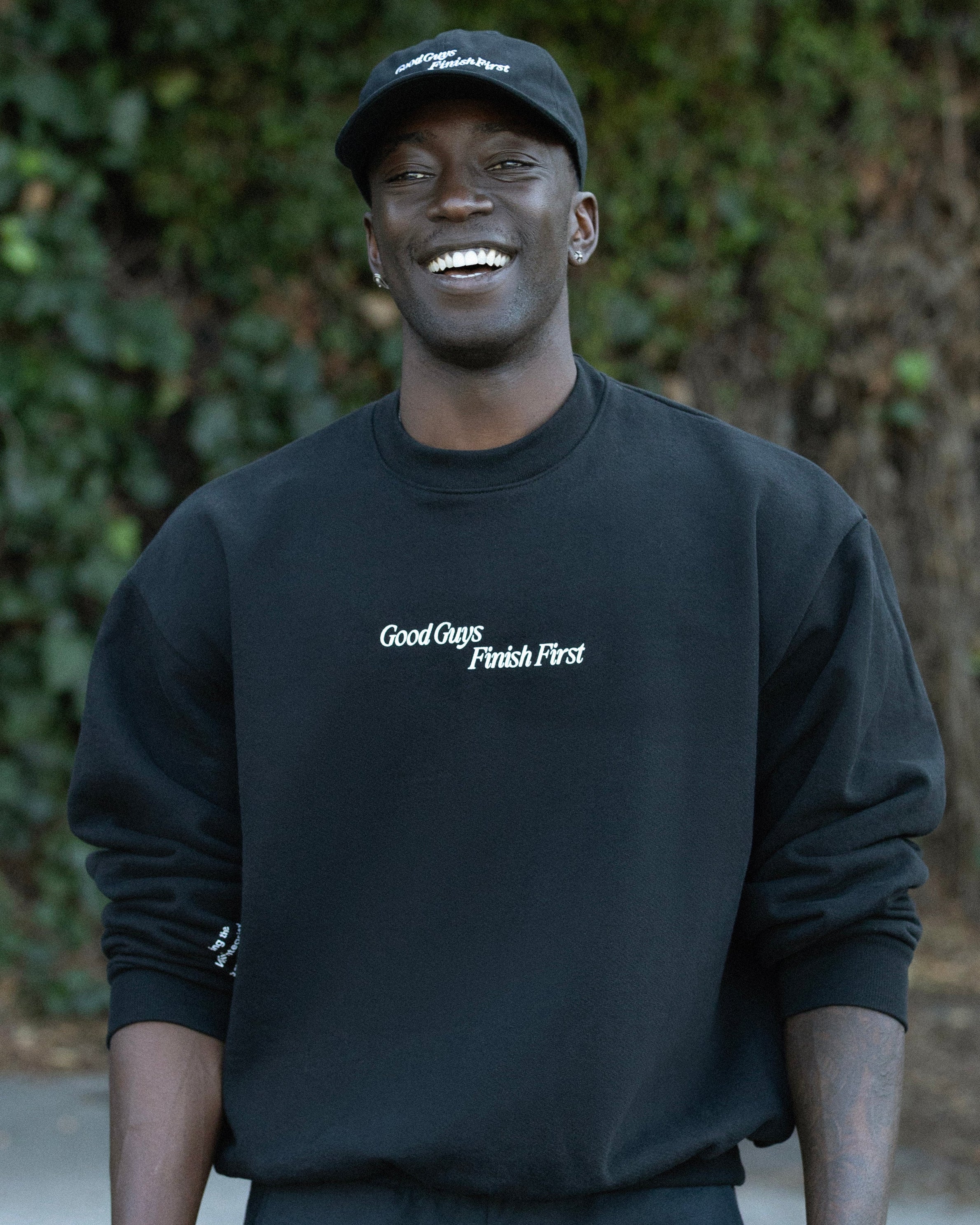 Person wearing a black sweatshirt with text, standing outdoors.